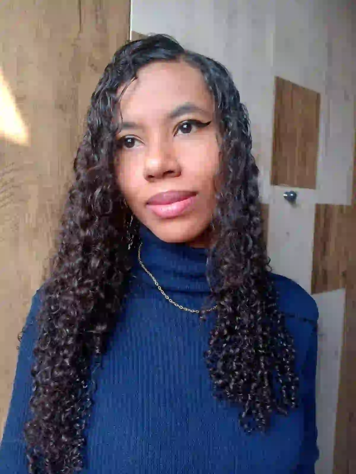 Retrato de Marine, fundadora do Fio de Aurora, com cabelo cacheado e suéter azul escuro.